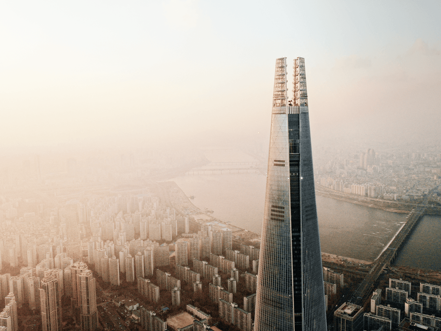 Aerial view of a tall modern skyscraper rising above a dense cityscape.